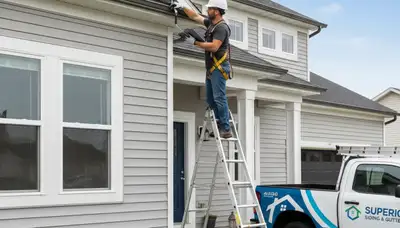 Technician performing gutter inspection on Raleigh NC home with vinyl siding exterior